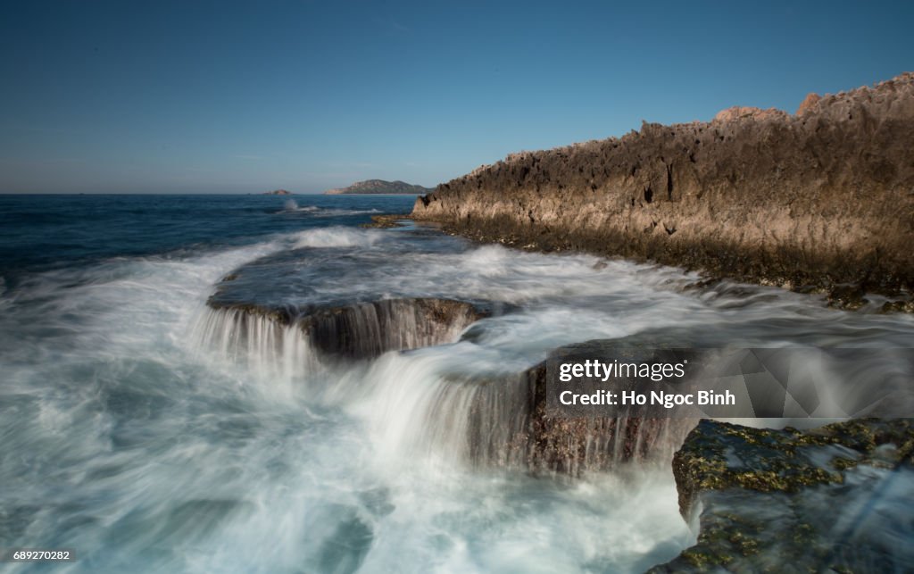 Big waves struck coral rock coast at HangRai Cave, Ninhthuan, Vietnam creating a waterfall in the ocean