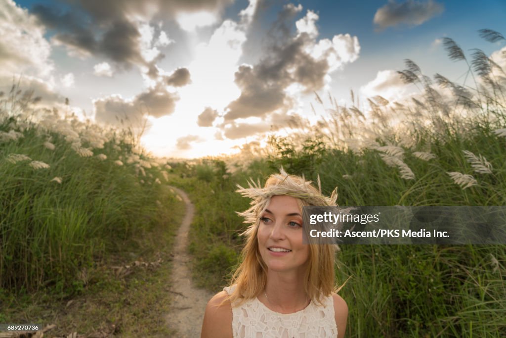 Young woman pauses in field of rushes, sunrise