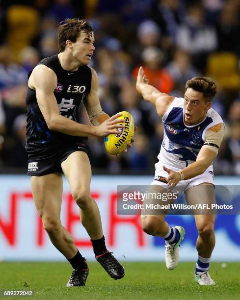 Lachie Plowman of the Blues is chased by Nathan Hrovat of the Kangaroos during the 2017 AFL round 10 match between the Carlton Blues and the North...