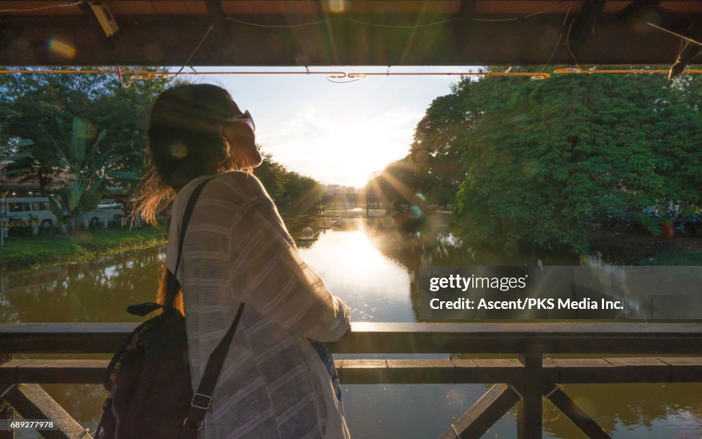 Young woman traverses bridge above tranquil river