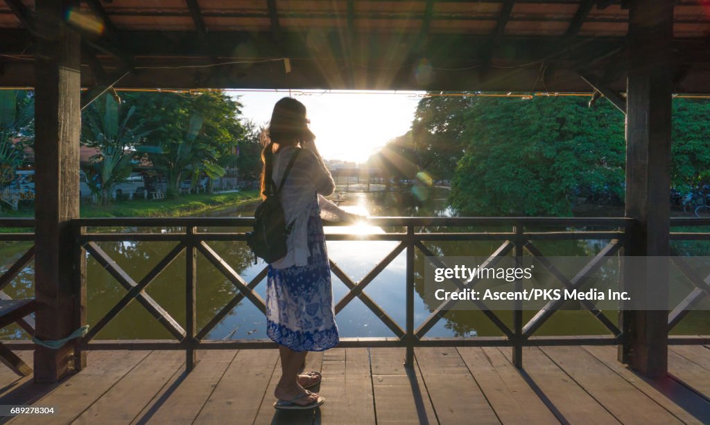 Young woman traverses bridge above tranquil river