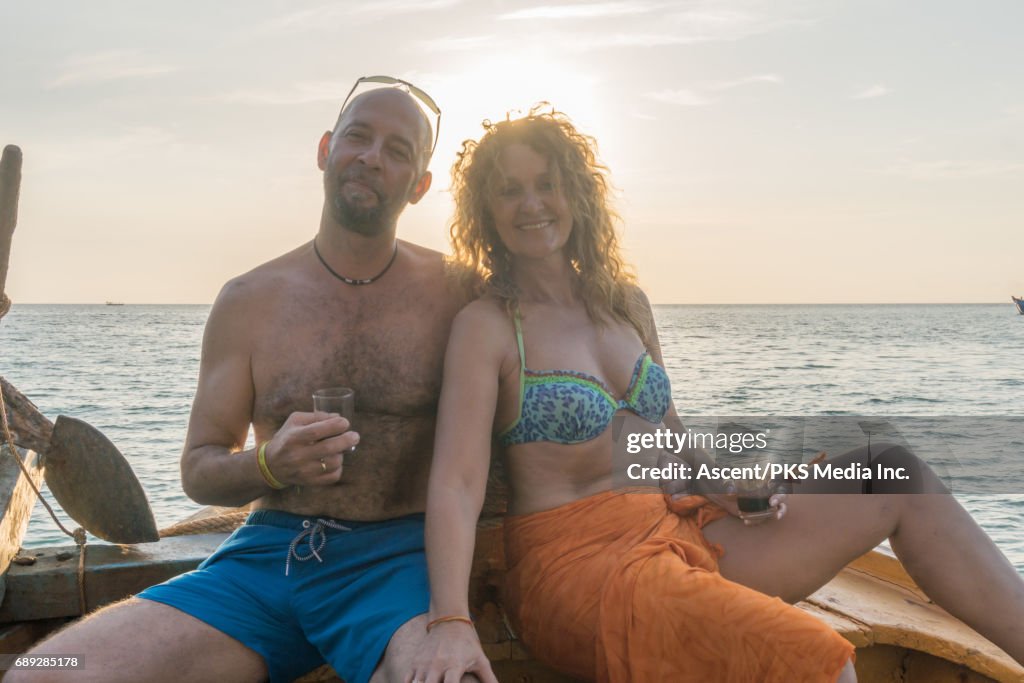 Mature couple enjoys wine on wooden deck at sunset