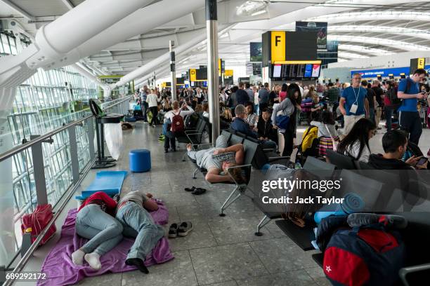 People sleep on a blanket at Heathrow Airport Terminal 5 on May 28, 2017 in London, England. Thousands of passengers face a second day of travel...