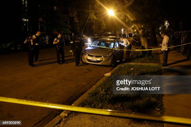 Chicago Police officer and detective investigate a vehicle at the crime scene where a man was shot in the North Lawndale neighborhood on May 28, 2017...