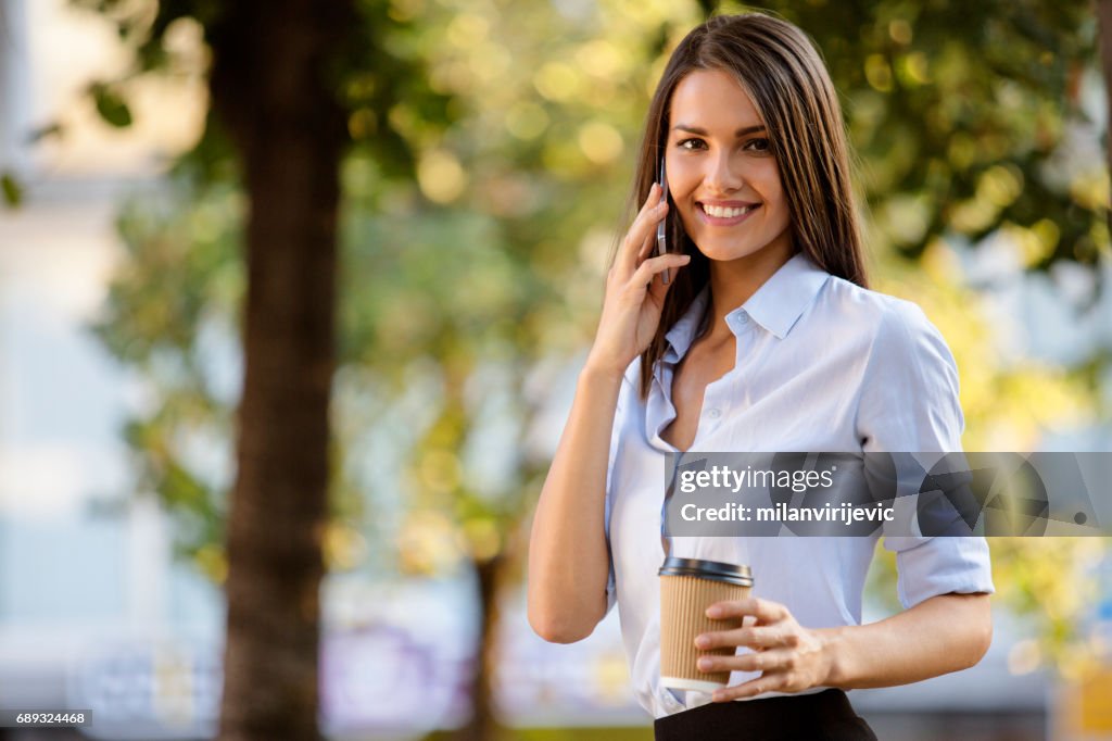 Fala menina bonita no telefone segurando a xícara de café