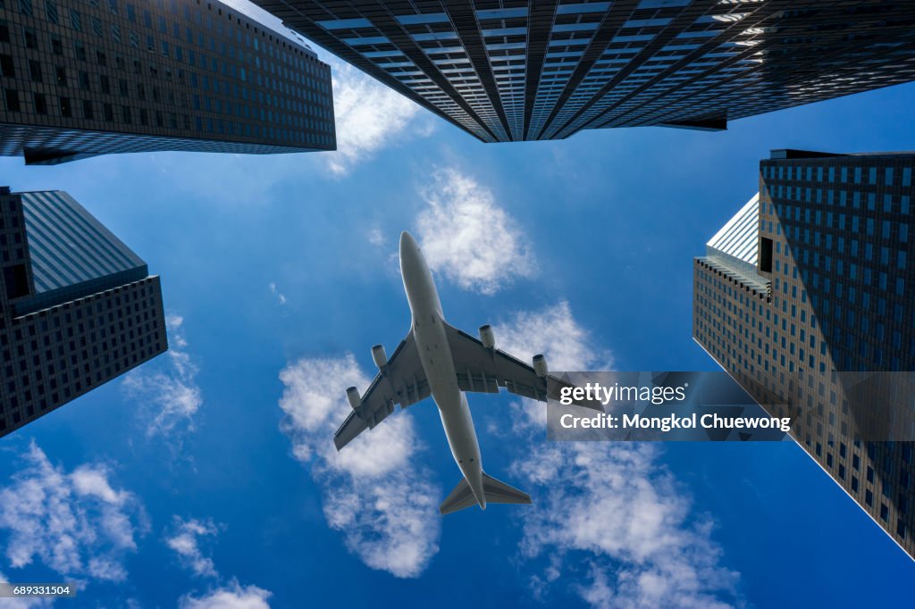 Commercial airplane flying over modern building