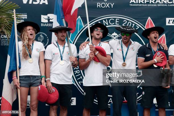 French surfing team members Justine Dupont, Joan Duru, Dimitri Ouvre, Vincent Duvignac and Jeremy Flores celebrate on the podium after winning the...