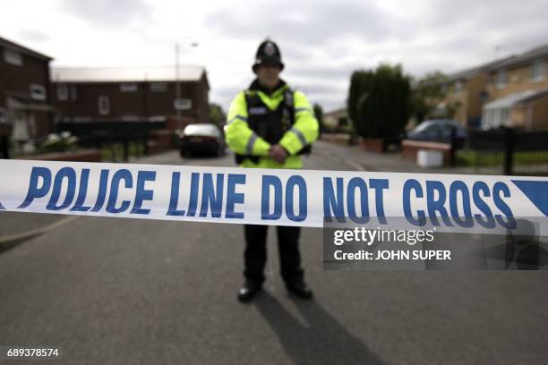 Police officer guards the entrance to a street in the Moss Side area of Manchester on May 28, 2017 during an operation. A British minister said...