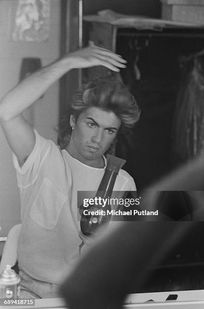 British singer-songwriter George Michael of Wham!, blow drying his hair during the pop duo's 1985 world tour, January 1985.'The Big Tour' took in the...
