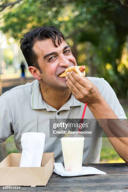 smiling mature man having a hot dog - asian eating hotdog stock pictures, royalty-free photos & images