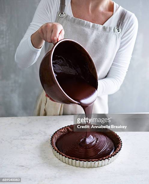 woman pouring chocolate into a tart pan - baking dish stock pictures, royalty-free photos & images