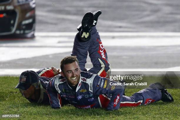 Austin Dillon, driver of the DOW Salutes Veterans Chevrolet, and his crew slide in the infield grass in celebration of winning the Monster Energy...