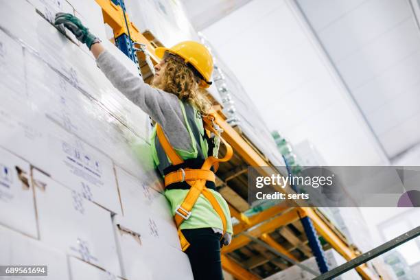 junge weibliche arbeiter hängen an einem kletterseil in lager - sicherheitsgurt sicherheitsausrüstung stock-fotos und bilder