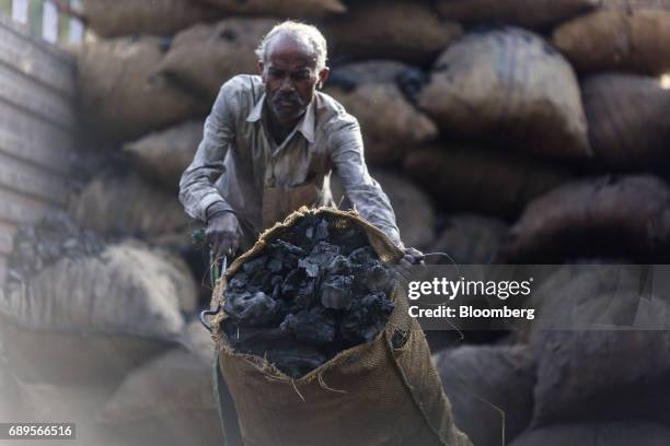 Workers unloads a sack of coal from a truck at a wholesale supplier's in New Delhi, India, on Sunday, May 28, 2017. India's ailing electricity...