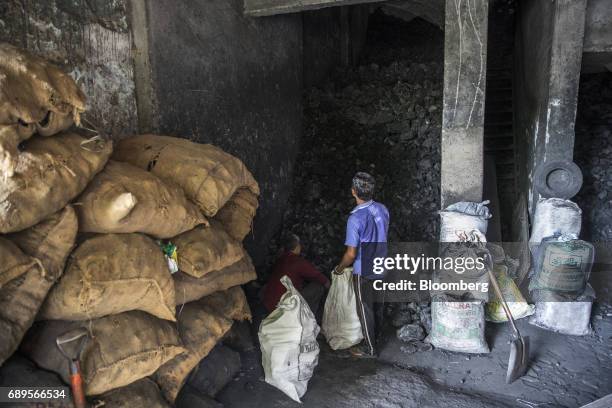 Workers load coal into a sack at a wholesale supplier's in New Delhi, India, on Sunday, May 28, 2017. India's ailing electricity distributors may...