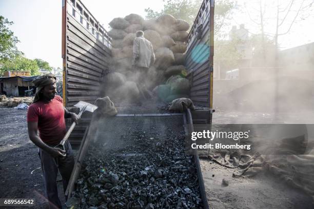 Workers unload coal from a truck at a wholesale supplier's in New Delhi, India, on Sunday, May 28, 2017. India's ailing electricity distributors may...