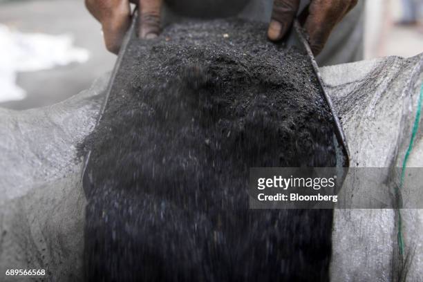 Worker pours coal dust into a sack at a wholesale supplier's in New Delhi, India, on Sunday, May 28, 2017. India's ailing electricity distributors...