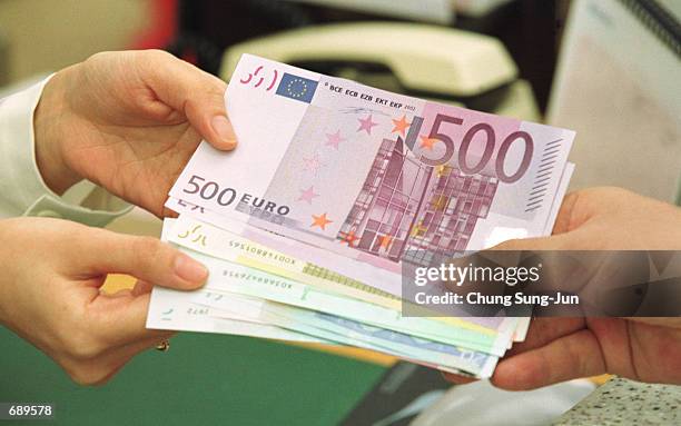 South Korean bank employee gives change in euro banknotes January 2, 2002 at the headquarters of the Korea Exchange Bank in Seoul, South Korea. South...