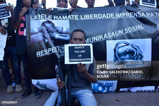 East Timorese journalist Raimundos Oki holds a placard during a rally to support him, who is charged with defamation, in Dili on May 29, 2017. A...