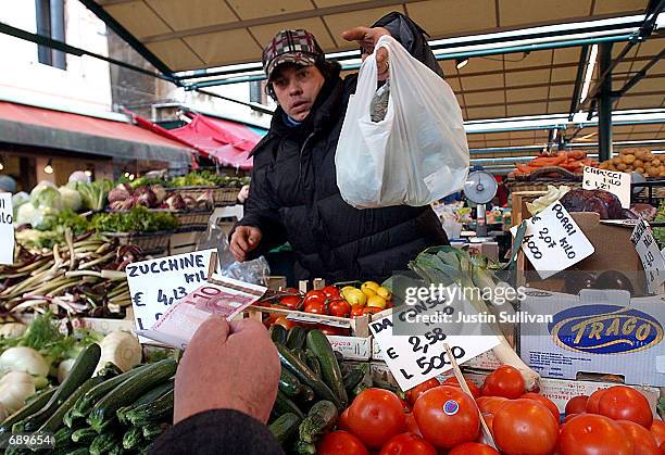 Customer prepares to pay for produce with Euro notes January 3, 2002 at the Rialto outdoor market in Venice, Italy. The Euro Dollar went into effect...