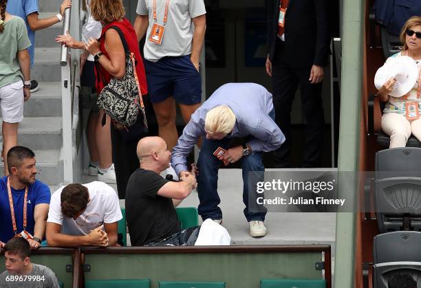 Andre Agassi, coach of Novak Djokovic speaks with Boris Becker on day two of the 2017 French Open at Roland Garros on May 29, 2017 in Paris, France.