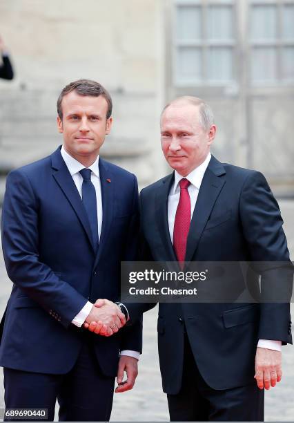 French President Emmanuel Macron welcomes Russian President Vladimir Putin prior to their meeting at "Chateau de Versailles" on May 29, 2017 in...