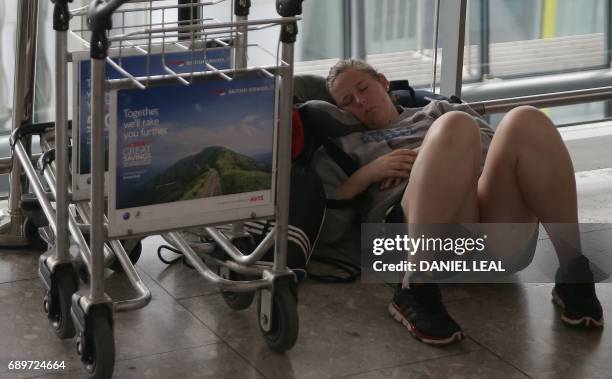 Passenger, directly affected by a global computer crash that disrupted British Airways flights, rests on the floor of Terminal 5 of London's Heathrow...