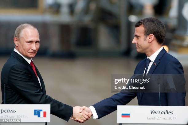 Russian President Vladimir Putin shakes hands with French President Emmanuel Macron after a joint press conference at "Chateau de Versailles" on May...