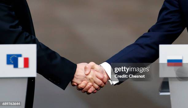 Russian President Vladimir Putin shakes hands with French President Emmanuel Macron after a joint press conference at "Chateau de Versailles" on May...