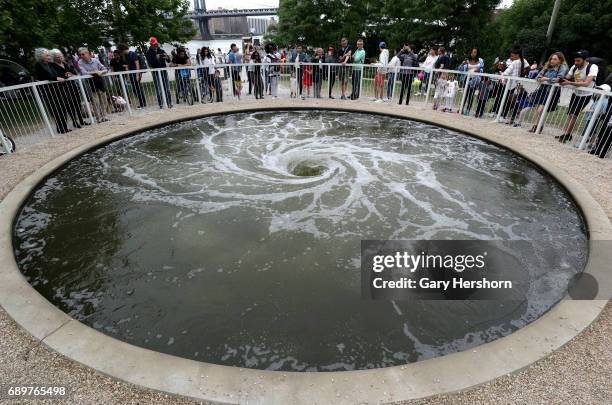 People look at the art installation "Descension" by Indian artist Anish Kapoor in Brooklyn Bridge Park on May 27, 2017 in New York City.