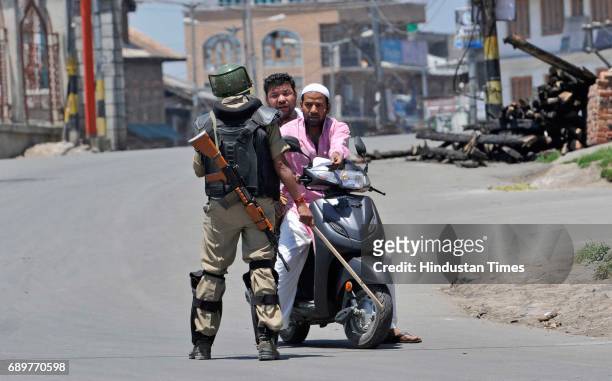 Paramilitary soldier stops Kashmiri men during curfew on May 29, 2017 in downtown area of Srinagar, India. The government imposed strict curfew in...