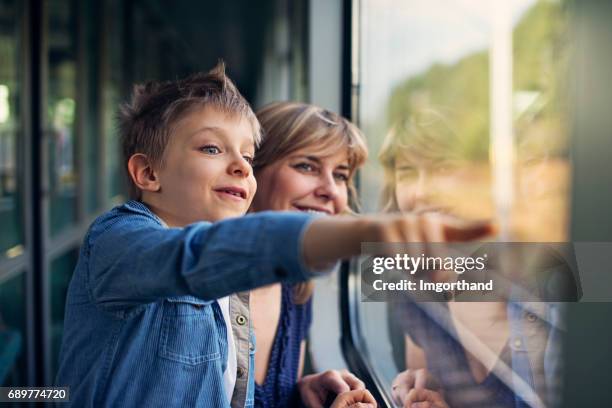 happy little boy travelling on train with mother - railing stock pictures, royalty-free photos & images