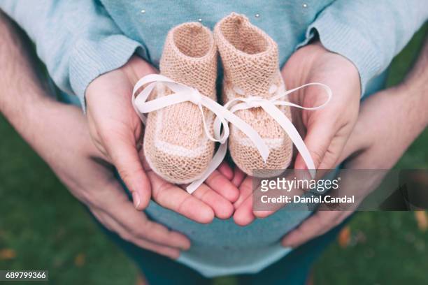 couple holding baby booties in hands - 赤ちゃんの靴 ストックフォトと画像