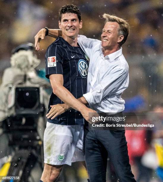 Mario Gomez of VfL Wolfsburg and head coach Andries Jonker of VfL Wolfsburg celebrate the continuance in the first Bundesliga after winning the...