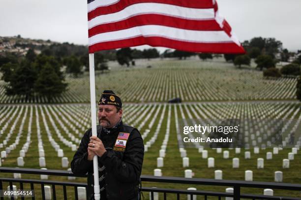 Navy Veteran Cory Wadding holds an American flag during a Memorial Day ceremony at the Golden Gate National Cemetery in San Bruno, CA, United States...