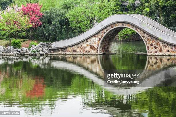 stone bridge reflected in the lake - garden bridge stockfoto's en -beelden