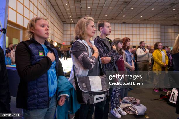 Guests stand and cover their hearts as the U.S. Navy Band performs at the JFK100 Celebration at the John F. Kennedy Presidential Library on May 29,...