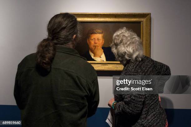 Guests check out a portrait of President John F. Kennedy on display at the JFK 100: Milestones & Mementos Exhibit at the John F. Kennedy Presidential...