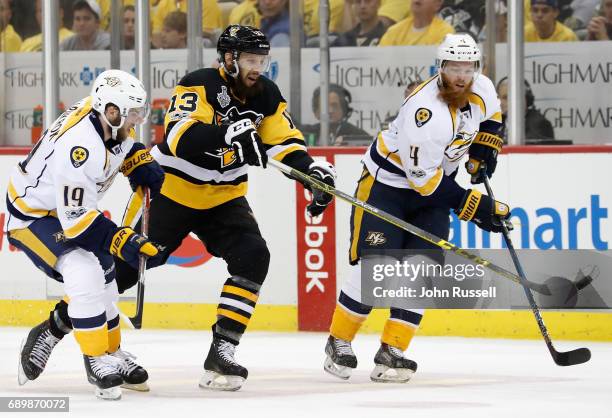Nick Bonino of the Pittsburgh Penguins taps the puck away from Calle Jarnkrok and Ryan Ellis of the Nashville Predators during the first period of...