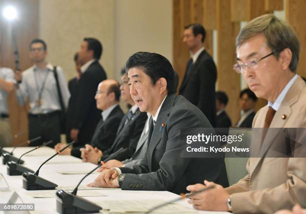 Japanese Prime Minister Shinzo Abe speaks, alongside TPP minister Nobuteru Ishihara , at a meeting of economic ministers in Tokyo on May 30 on the...