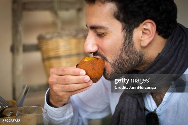 sicily: young man eating traditional arancina (croquette) - appetiser stock pictures, royalty-free photos & images