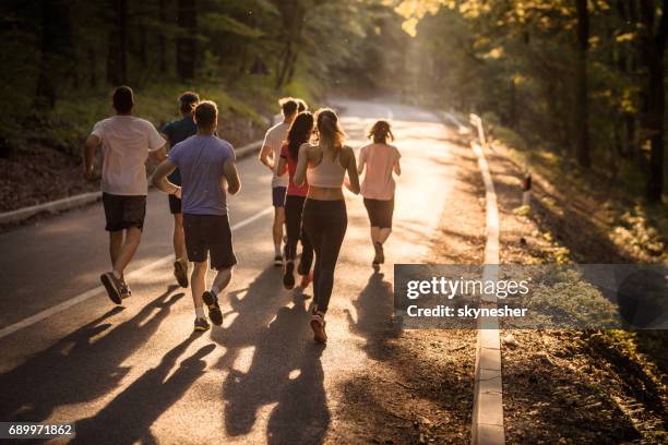 vista posteriore dei maratoneti che corrono al tramonto. - 10000 metri foto e immagini stock