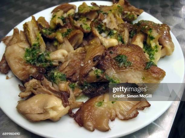 tapas of pan-fried oyster mushrooms with salsa verde on a white plate on a stainless steel tabletop - pleurote photos et images de collection