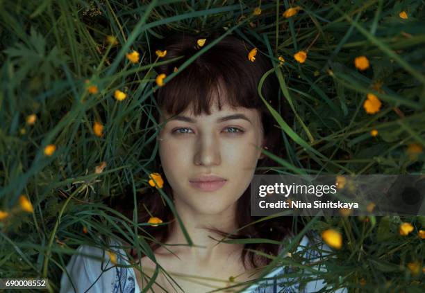 woman laying down in green grass and yellow flowers - lying on grass stock-fotos und bilder