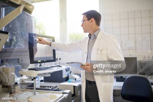 male scientist using computer with tablet - scientist standing next to table stock pictures, royalty-free photos & images