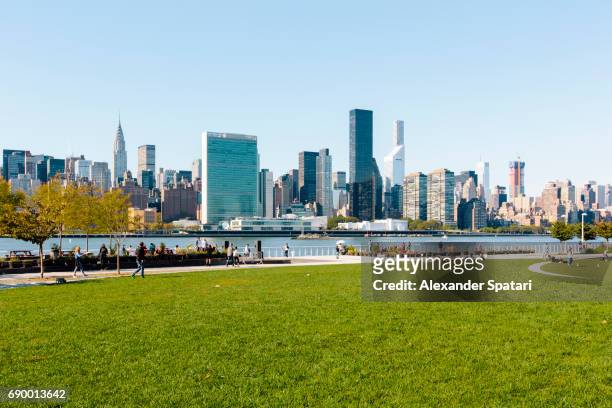 manhattan skyline along east river with green lawn on the foreground, new york city, usa - urban areas　water front stock pictures, royalty-free photos & images