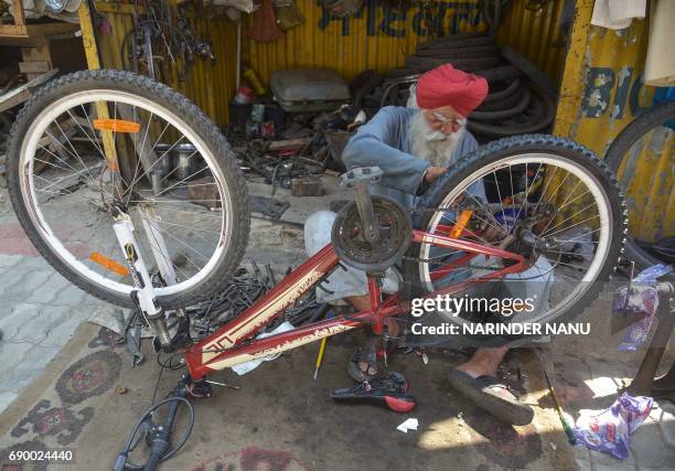 Indian mechanic Hardev Singh repairs a bicycle at his shop in Amritsar on May 30, 2017. Singh said he earns around 300-600 INR a day for his bicycle...