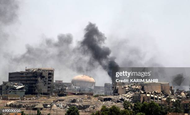 Smoke billows in a neighbourhood of west Mosul's near Al-Shifa hospital on May 30, 2017 during ongoing battles between Iraqi forces to retake the...