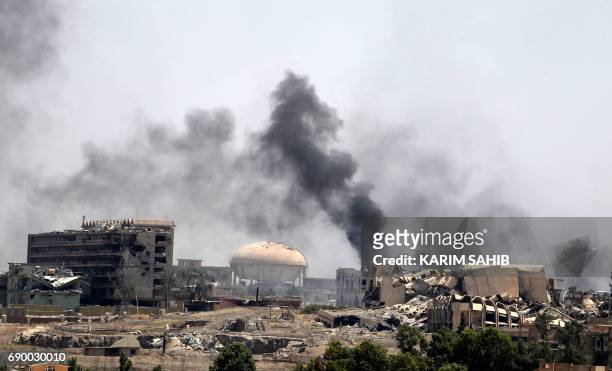 Smoke billows in a neighbourhood of west Mosul's near Al-Shifa hospital on May 30, 2017 during ongoing battles between Iraqi forces to retake the...