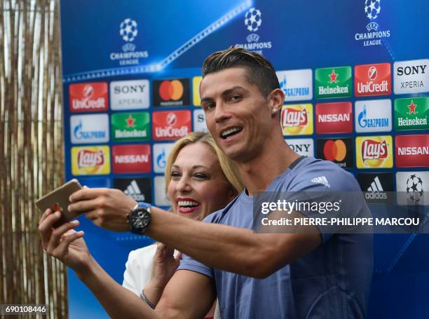 Real Madrid's Portuguese forward Cristiano Ronaldo takes a selfie with a journalist in the mixed zone at Valdebebas Sport City in Madrid on May 30,...